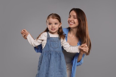 Photo of Happy mother with her cute little daughter on grey background