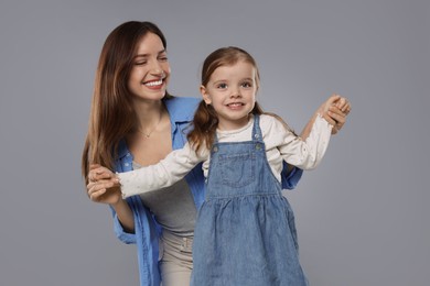 Photo of Happy mother with her cute little daughter on grey background