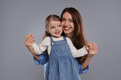 Photo of Portrait of happy mother with her cute little daughter on grey background