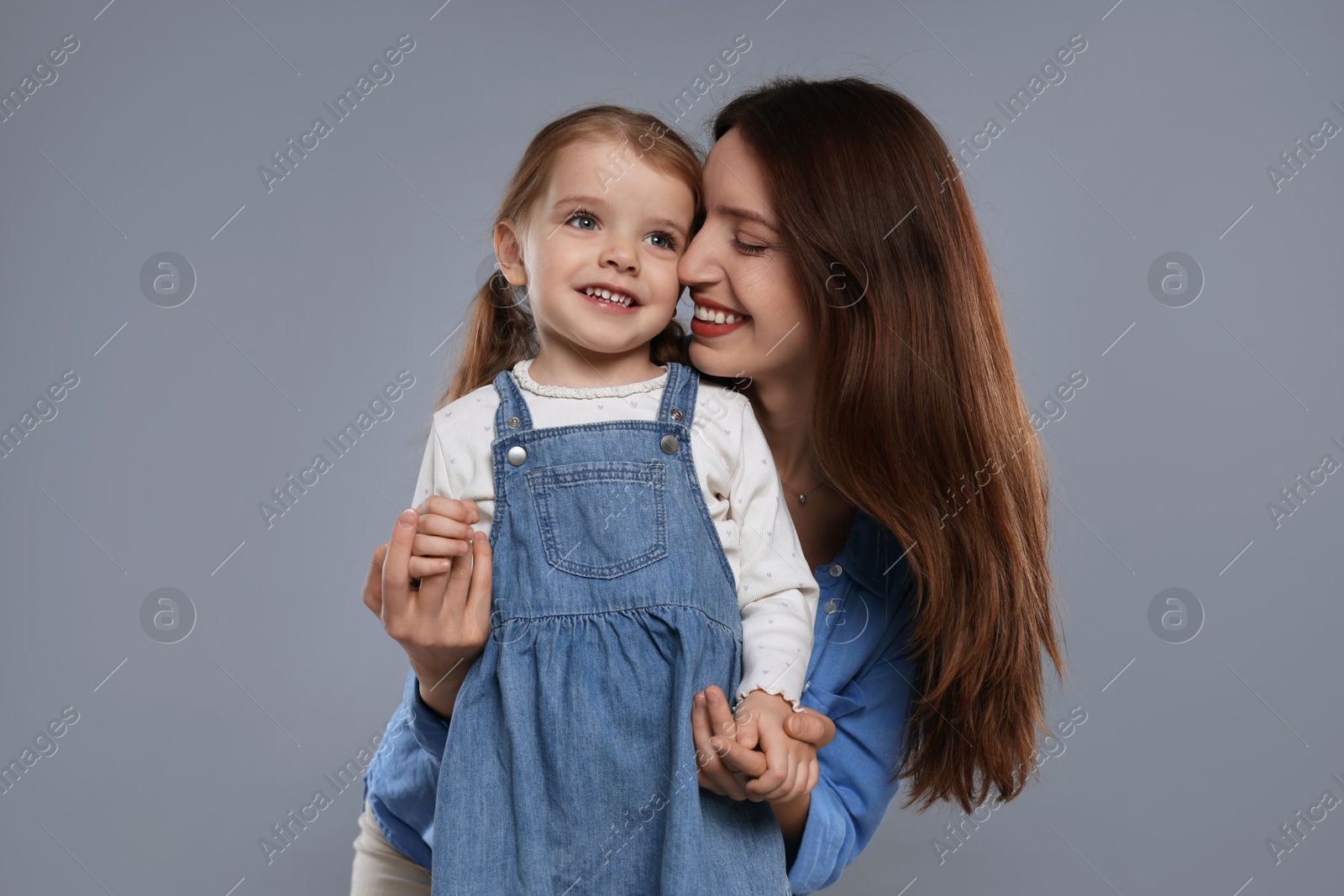 Photo of Happy mother with her cute little daughter on grey background