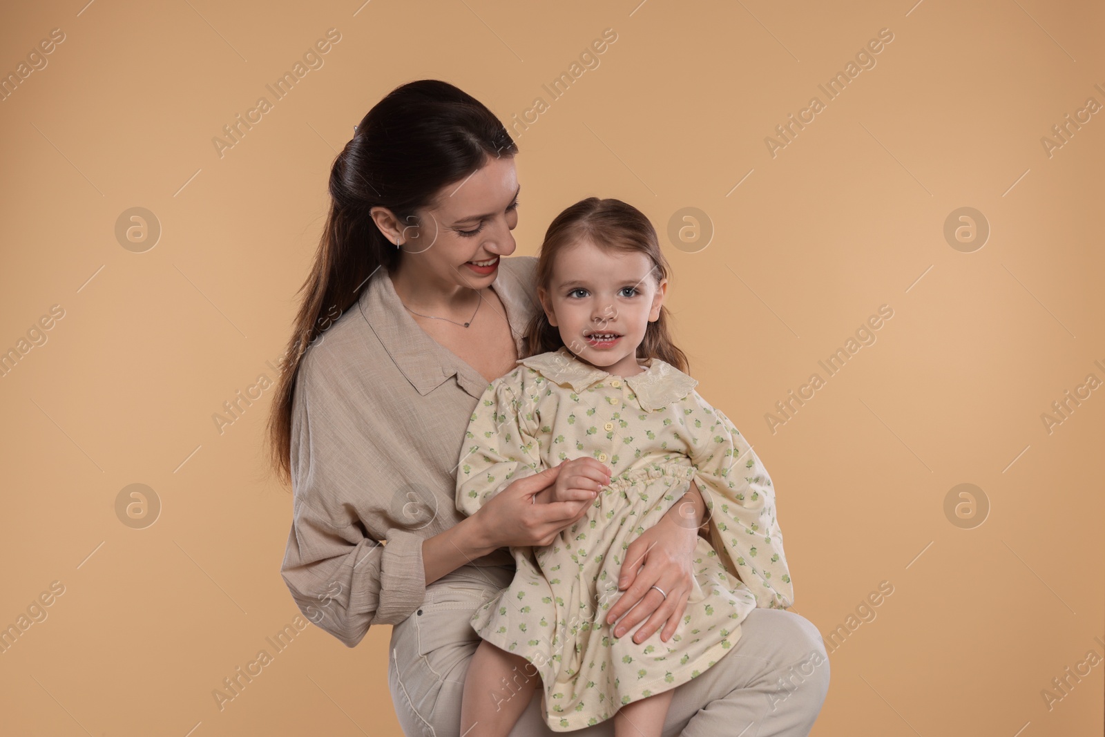 Photo of Happy mother with her cute little daughter on beige background