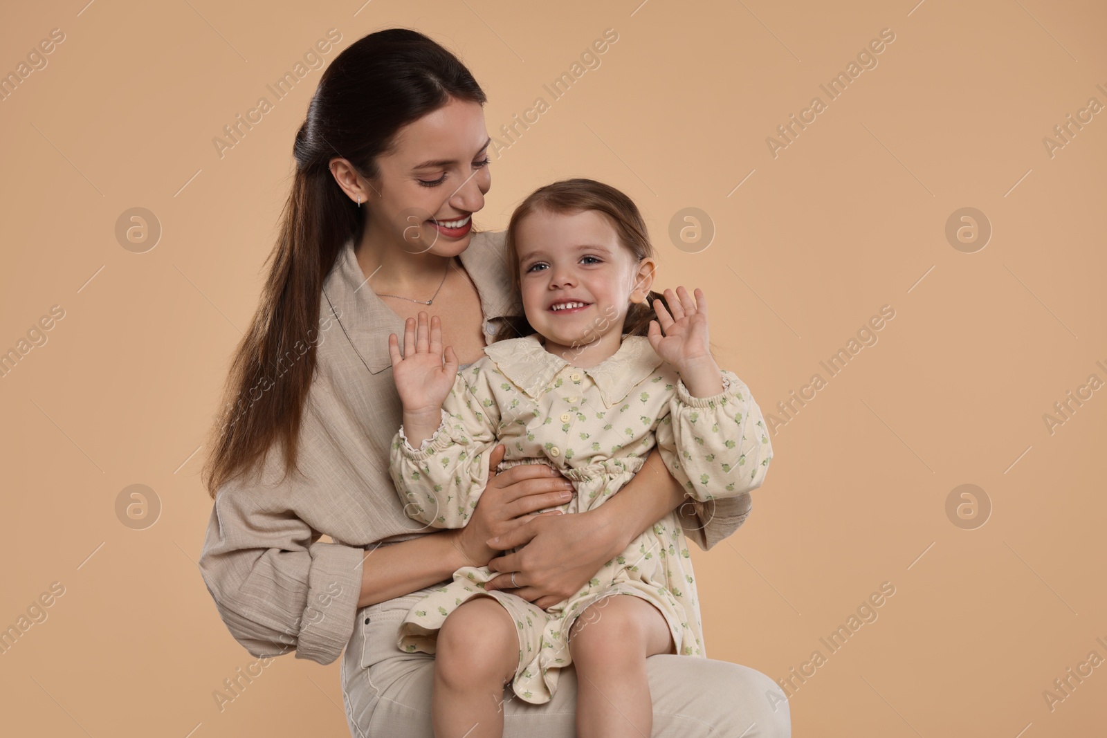 Photo of Happy mother with her cute little daughter on beige background