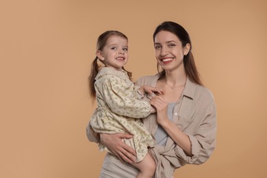 Photo of Portrait of happy mother with her cute little daughter on beige background