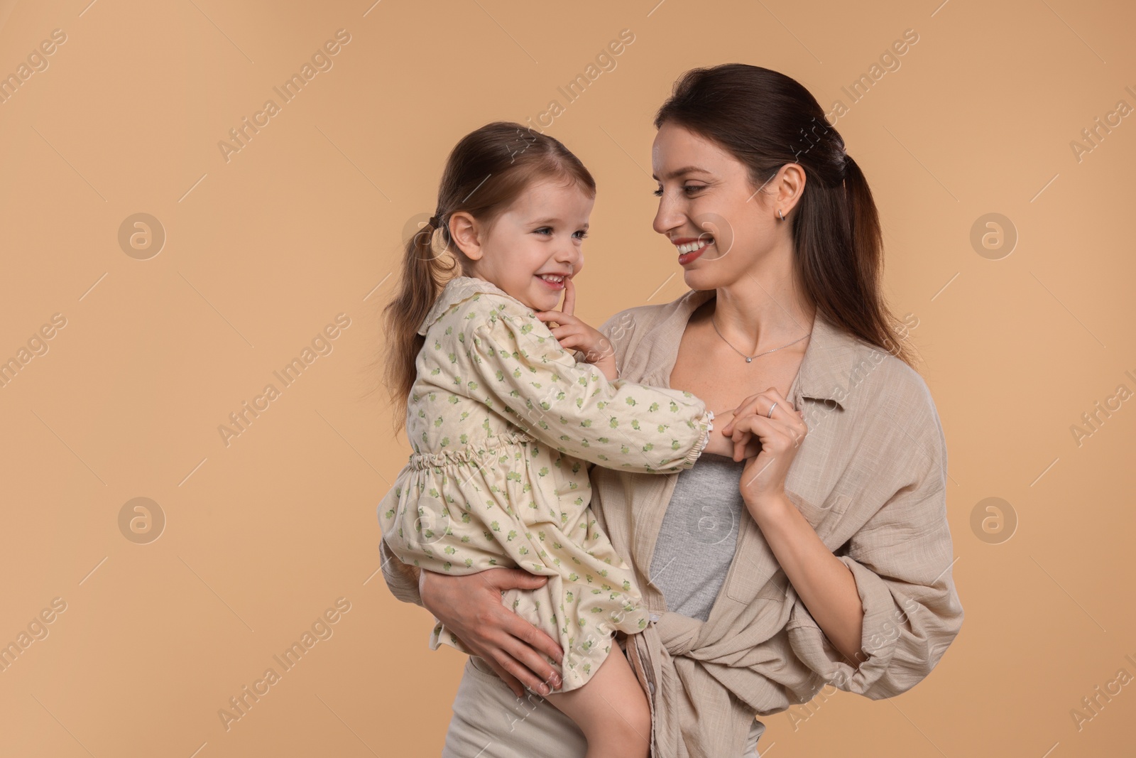 Photo of Happy mother with her cute little daughter on beige background