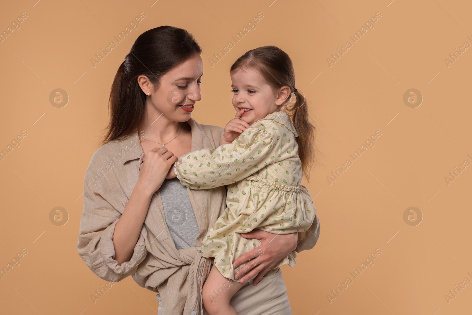 Photo of Happy mother with her cute little daughter on beige background