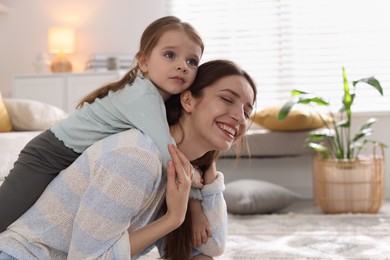 Photo of Happy mother having fun with her cute little daughter at home