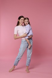 Happy mother with her cute little daughter on pink background