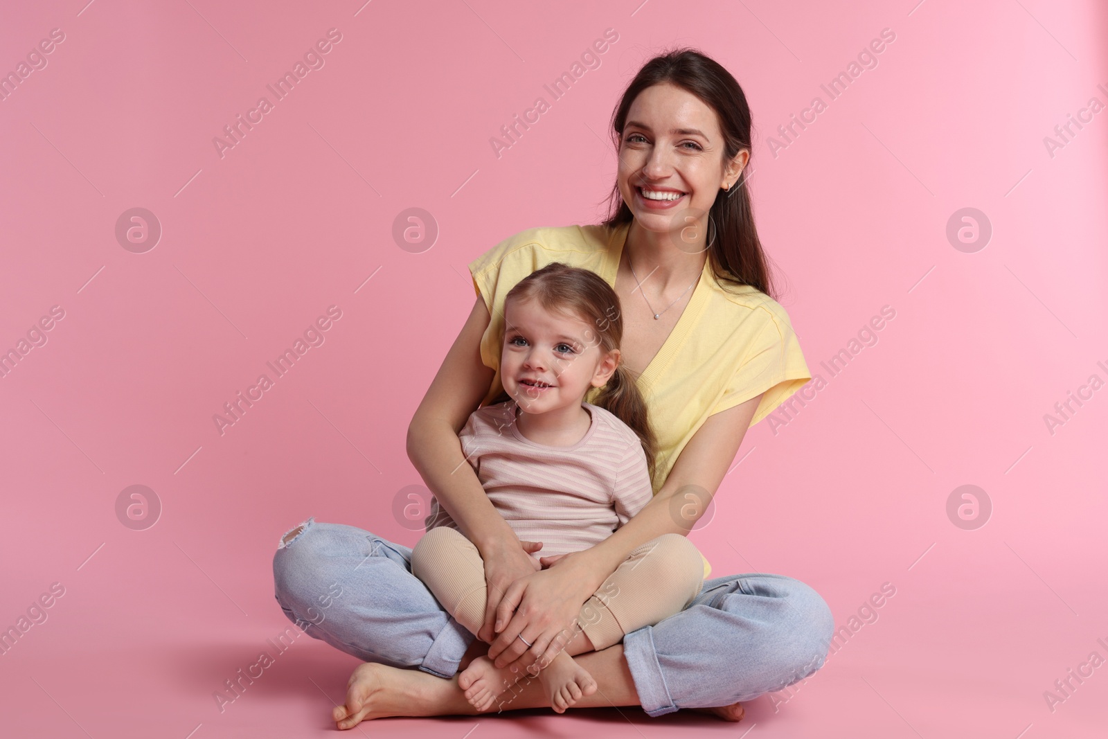 Photo of Happy mother with her cute little daughter on pink background