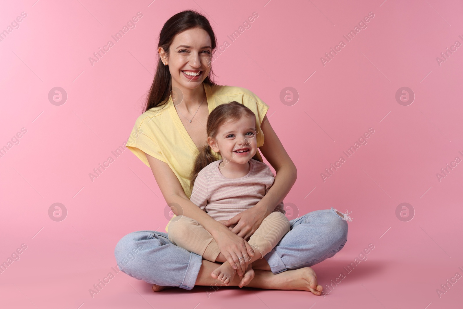 Photo of Happy mother with her cute little daughter on pink background