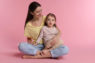 Photo of Happy mother with her cute little daughter on pink background. Space for text