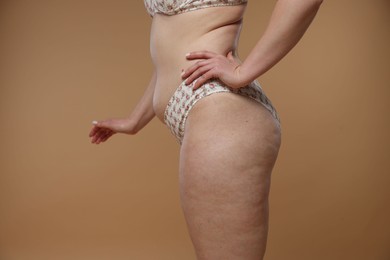 Photo of Woman with cellulite on dark beige background, closeup