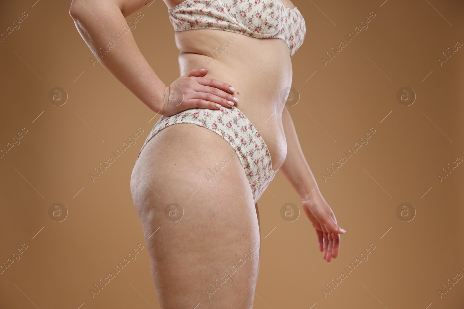 Photo of Woman with cellulite on dark beige background, closeup