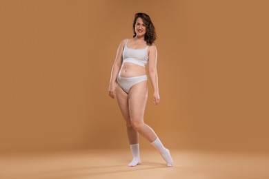 Photo of Beautiful woman in underwear on dark beige background. Cellulite problem