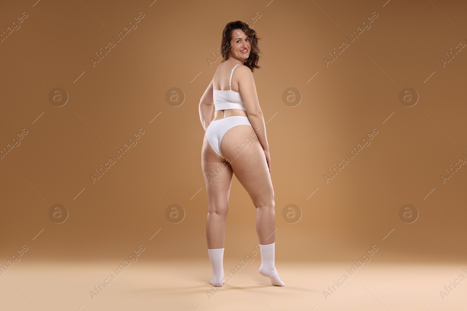 Photo of Beautiful woman in underwear on dark beige background. Cellulite problem