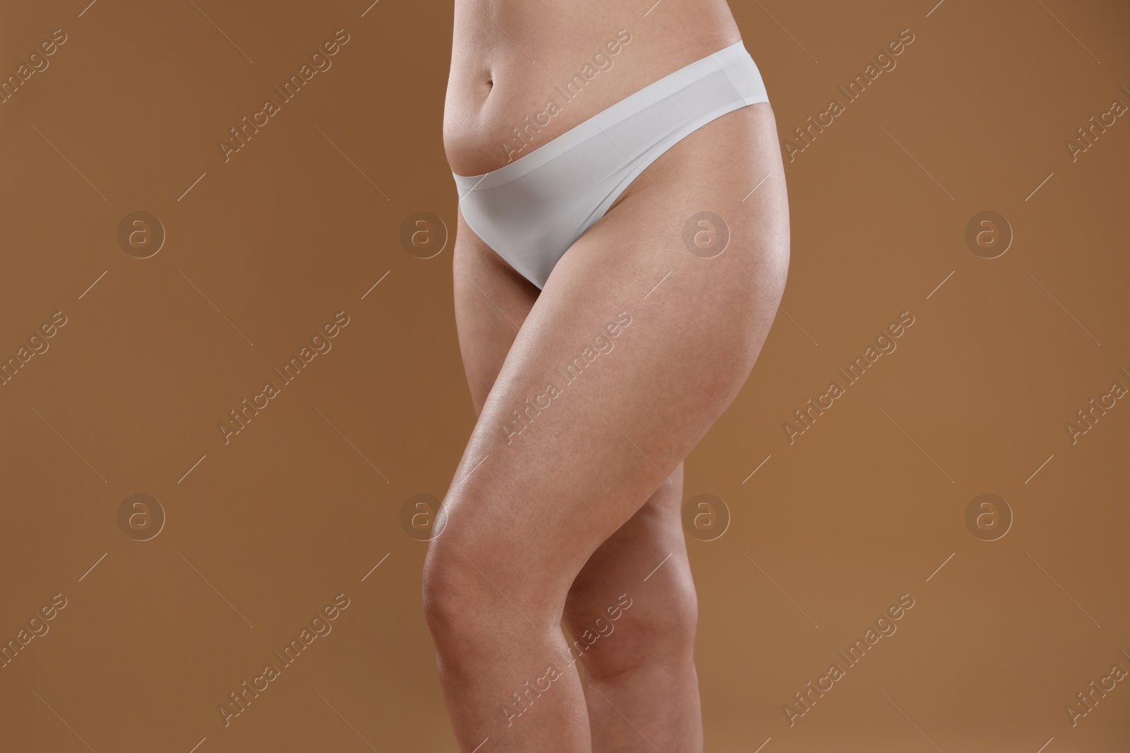 Photo of Woman with cellulite on light brown background, closeup