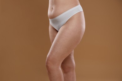 Photo of Woman with cellulite on light brown background, closeup