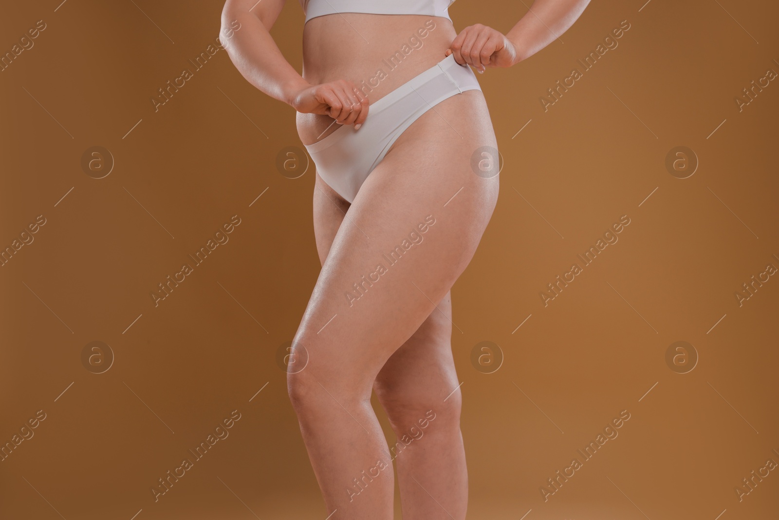 Photo of Woman with cellulite on light brown background, closeup