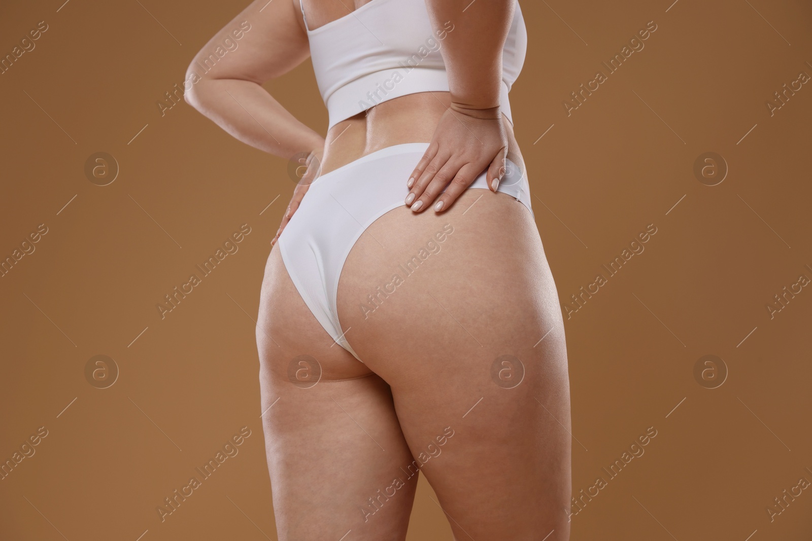 Photo of Woman with cellulite on light brown background, closeup