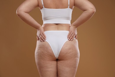 Photo of Woman with cellulite on light brown background, closeup