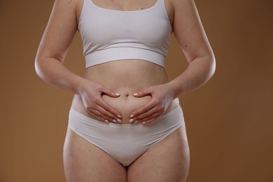 Photo of Woman with cellulite on light brown background, closeup