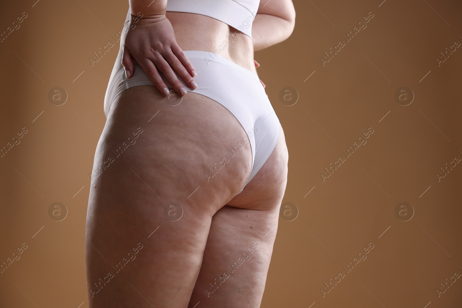 Photo of Woman with cellulite on light brown background, closeup