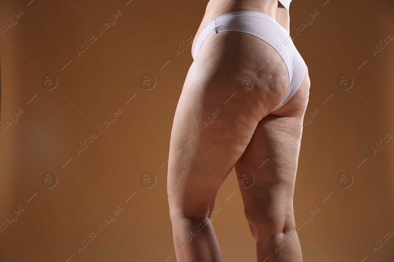 Photo of Woman with cellulite problem on brown background, closeup. Space for text