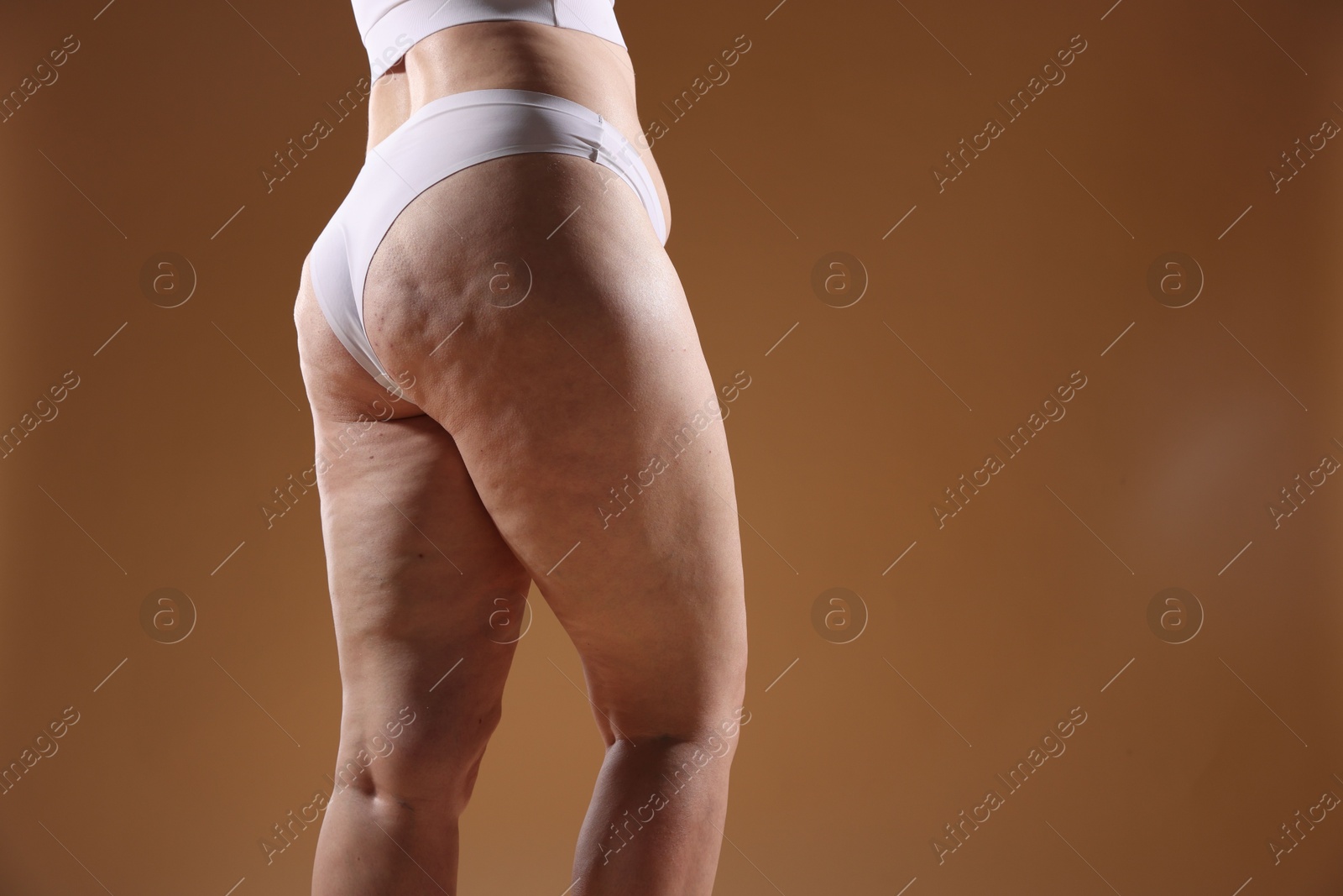 Photo of Woman with cellulite problem on brown background, closeup. Space for text