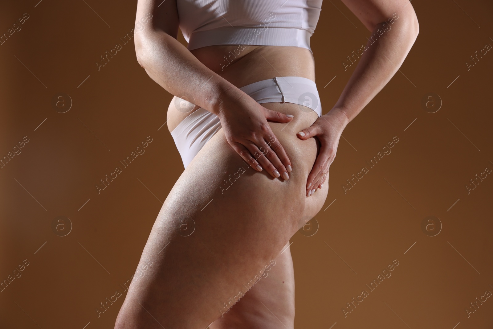 Photo of Woman with cellulite problem on brown background, closeup