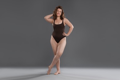 Photo of Beautiful woman in bodysuit on dark grey background. Cellulite problem