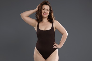 Photo of Beautiful woman in bodysuit on dark grey background. Cellulite problem