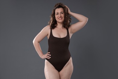 Photo of Beautiful woman in bodysuit on dark grey background. Cellulite problem