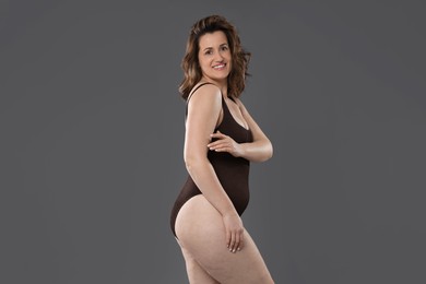 Photo of Beautiful woman in bodysuit on dark grey background. Cellulite problem