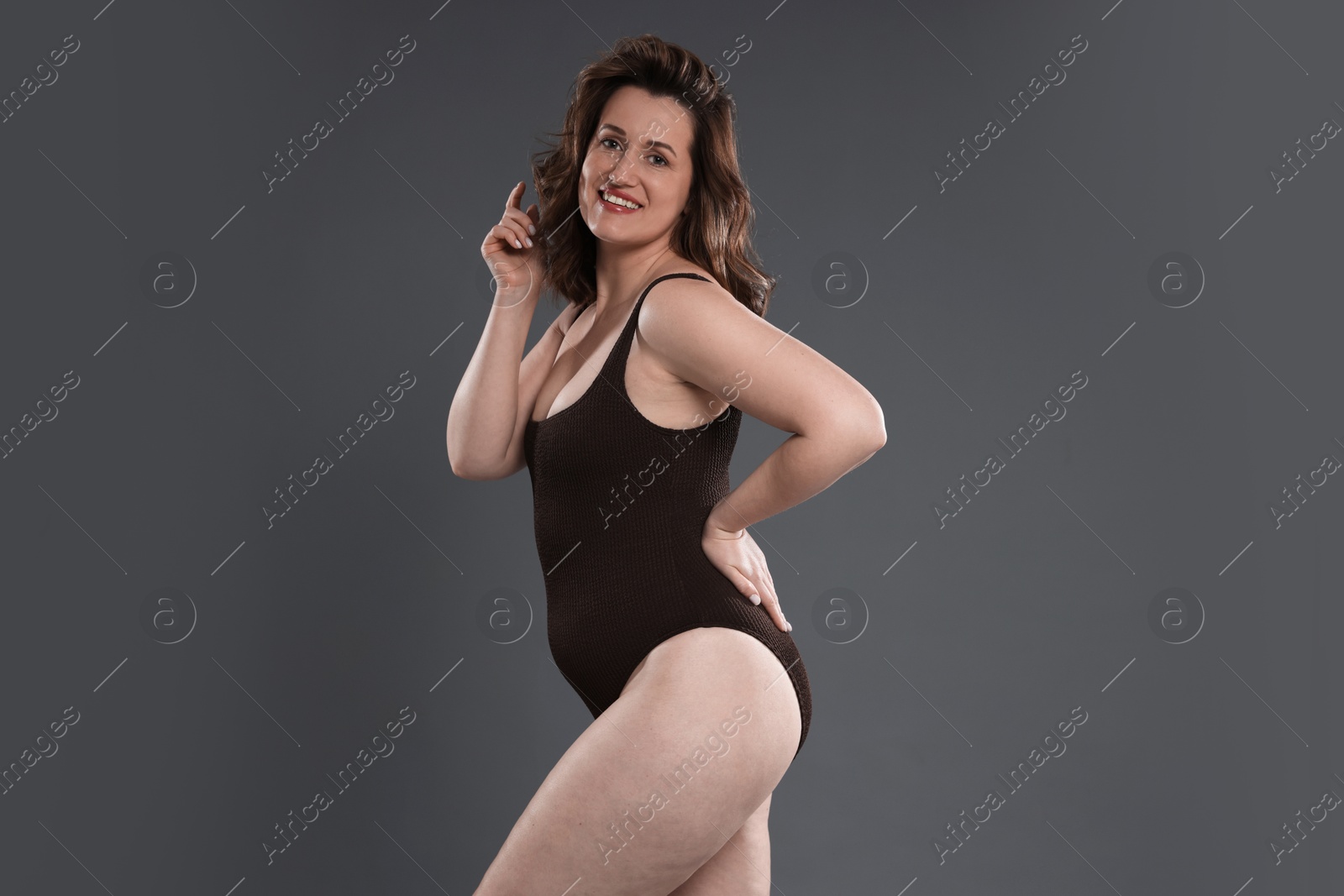 Photo of Beautiful woman in bodysuit on dark grey background. Cellulite problem