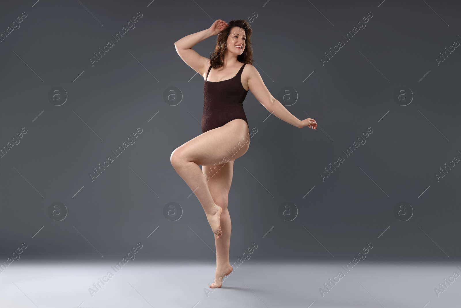 Photo of Beautiful woman in bodysuit on dark grey background. Cellulite problem