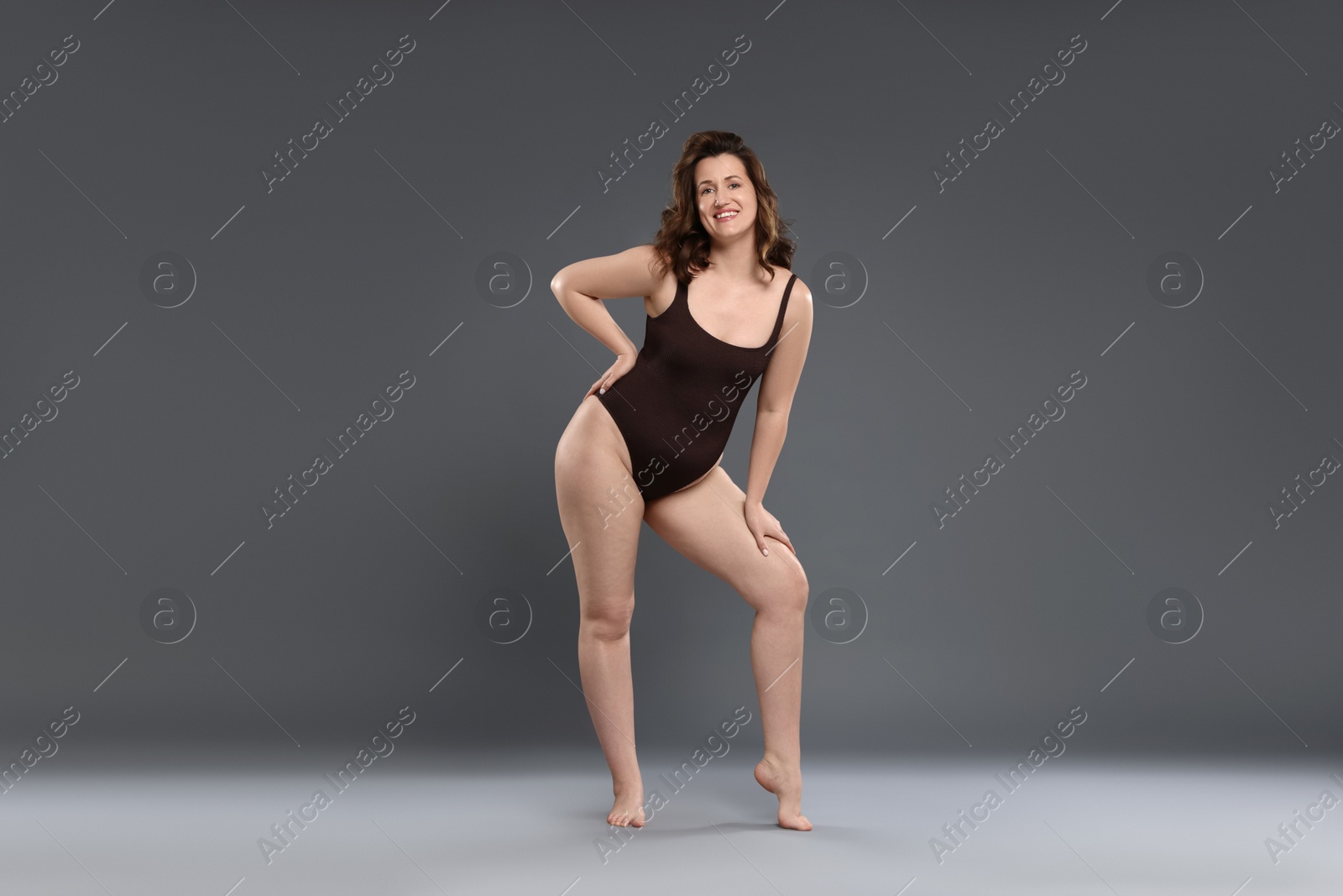 Photo of Beautiful woman in bodysuit on dark grey background. Cellulite problem