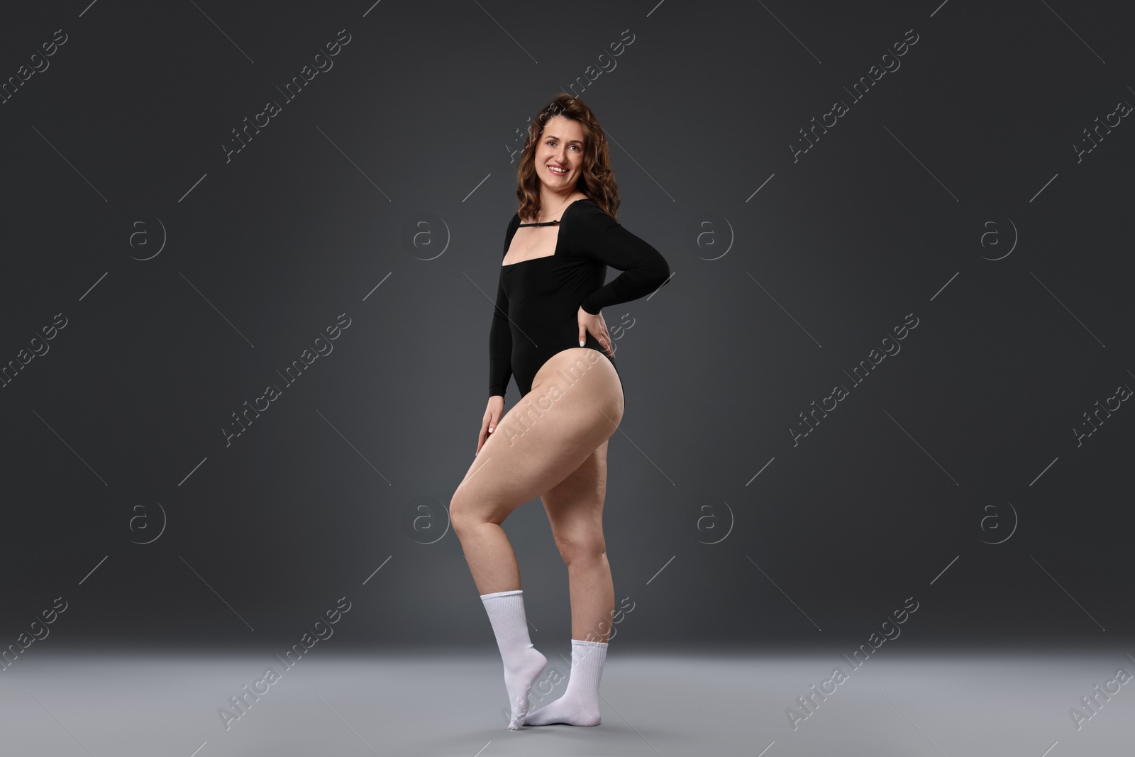 Photo of Beautiful woman in bodysuit on dark grey background. Cellulite problem