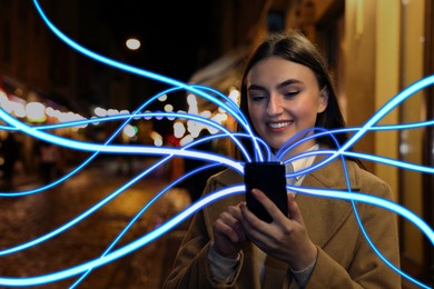 Image of Happy woman using mobile phone outdoors. Bright lines coming out of device symbolizing high speed internet