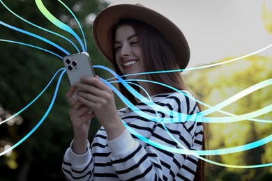 Image of Happy woman using mobile phone outdoors. Bright lines coming out of device symbolizing high speed internet