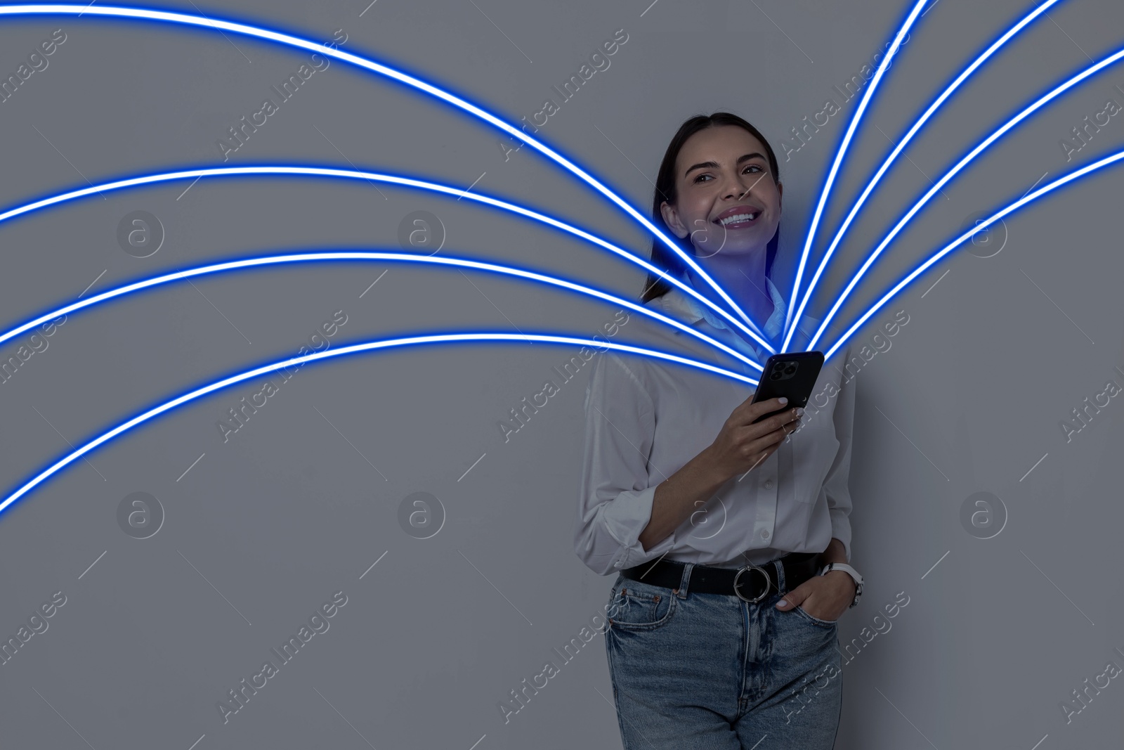 Image of Happy woman using mobile phone on grey background. Bright lines coming out of device symbolizing high speed internet