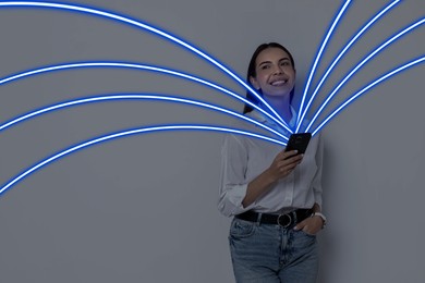 Image of Happy woman using mobile phone on grey background. Bright lines coming out of device symbolizing high speed internet