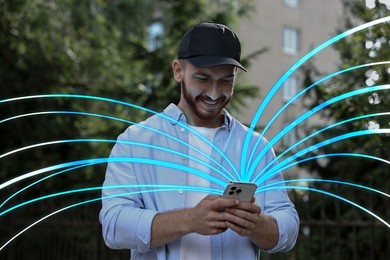 Image of Happy man using mobile phone outdoors. Bright lines coming out of device symbolizing high speed internet