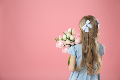 Photo of Cute little girl with bouquet of beautiful spring flowers on pink background, back view. Space for text