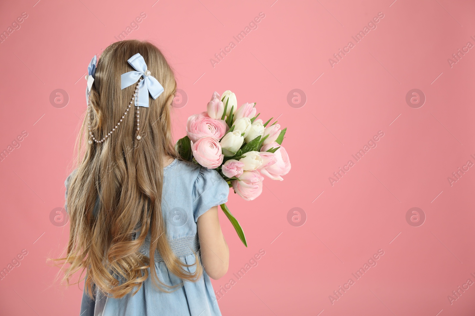 Photo of Cute little girl with bouquet of beautiful spring flowers on pink background, back view. Space for text