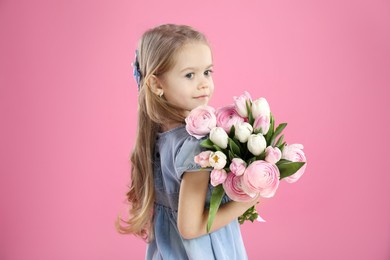 Cute little girl with bouquet of beautiful spring flowers on pink background