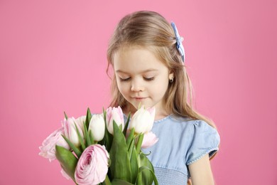 Photo of Cute little girl with bouquet of beautiful spring flowers on pink background