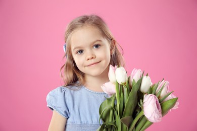 Photo of Cute little girl with bouquet of beautiful spring flowers on pink background