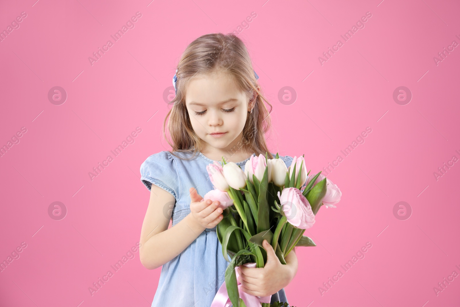 Photo of Cute little girl with bouquet of beautiful spring flowers on pink background