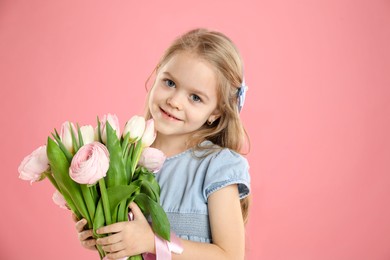 Cute little girl with bouquet of beautiful spring flowers on pink background