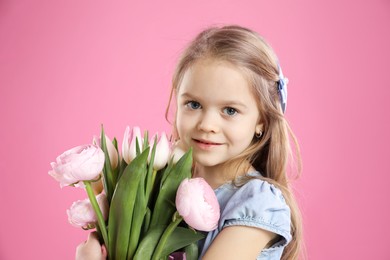 Photo of Cute little girl with bouquet of beautiful spring flowers on pink background