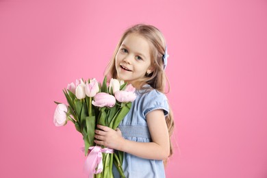 Photo of Cute little girl with bouquet of beautiful spring flowers on pink background